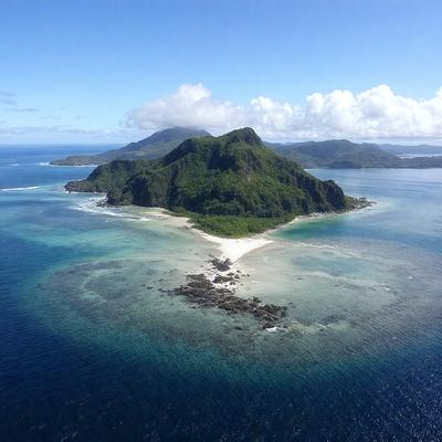 The primary subject of the image is a small island surrounded by a lagoon. The island is located in the middle of the ocean, and it appears to be a tropical paradise. The setting is a beautiful blue ocean with a clear sky, creating a serene and peaceful atmosphere. The visual style of the image is a photo, capturing the natural beauty of the island and its surroundings. The colors and mood of the image are predominantly blue and green, reflecting the calm and tranquil nature of the